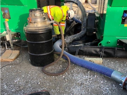 Technician operating vacuum and filtration equipment at an industrial release site