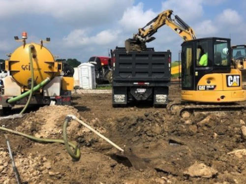 Vacuum trailer, dump truck and excavator removing impacted material from a site